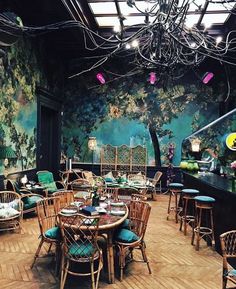 a dining room with tables and chairs in front of a tree painted on the wall