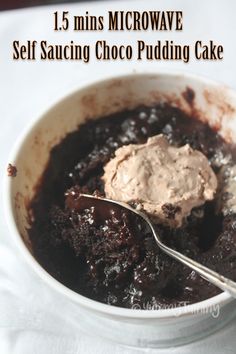 a bowl filled with brownie pudding on top of a white table cloth next to a spoon