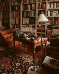 a living room filled with lots of books on top of a wooden table next to a lamp