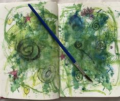 an open book with green and blue designs on the pages, next to a paintbrush