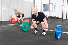 two men squatting down while holding barbells