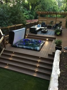 a hot tub sitting on top of a wooden deck next to a lush green field