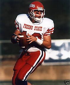 a football player is running with the ball in his hand and wearing a red uniform