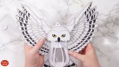 a person holding an owl shaped object on top of a marble counter with white and black accents