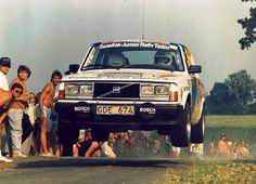 a group of men standing next to a white truck on top of a dirt road