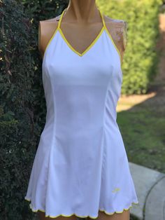 Here is a vintage 1970s white polyester tennis dress.Made by Mondessa.Following  are the measurements. Bust 32", waist 26",Hips 40",Length from top of shoulder to hem 29".Made out of a white polyester fabric.Has a built in bra.Yellow trim around neck and back. Has a yellow pocket on the back.In nice vintage condition.Please take special consideration of measurements. 1970s sizing was very small to today's standards. Tennis dresses were very short not like a regular dress. So please take special note of length. If you live overseas please email me first before purchasing for mailing cost. Price quoted is for USA only Tennis Dresses For Women, White Retro V-neck Dress, Sleeveless Spring Tennis Dress, Sleeveless Tennis Dress For Spring, Fitted V-neck Tennis Dress For Spring, Fitted V-neck Tennis Dress, White V-neck Tennis Dress For Spring, Fitted V-neck Tennis Dress For Summer, Fitted White Tennis Dress For Spring