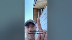 a man holding up his hand in front of a house with the words west help call written on it