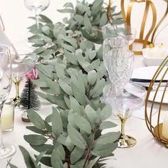 the table is set with silverware and greenery