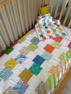 a baby crib with a colorful quilt on it