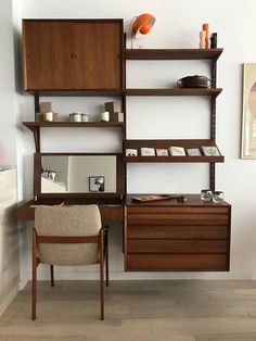 a wooden desk and chair in front of a wall mounted bookcase with shelves on it