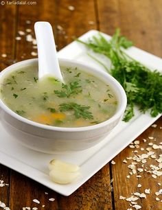 a white plate topped with a bowl of soup and garnished with parsley