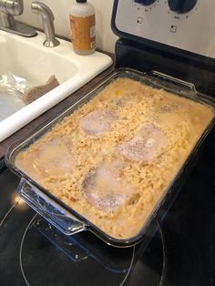 an uncooked casserole dish sitting on top of the stove next to a sink