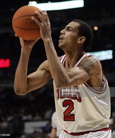 a basketball player taking a shot with the ball in his hand and looking up at it