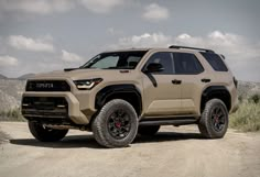 a tan toyota truck parked on top of a dirt road