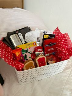 a basket filled with food sitting on top of a bed next to a white pillow