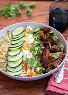 a bowl filled with meat, rice and cucumbers