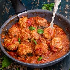 meatballs with tomato sauce and basil in a skillet on a wooden table, ready to be eaten