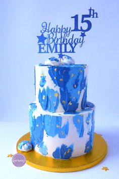 a blue and white birthday cake on a gold platter with the number 15 printed on it