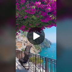 a bench sitting on top of a metal railing next to the ocean with purple flowers hanging over it