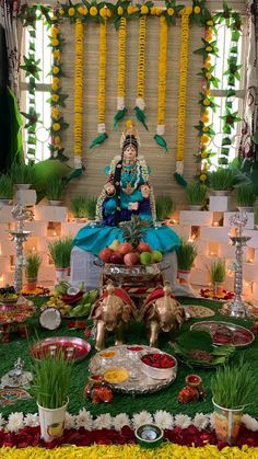 an idol sitting on top of a lush green field next to flowers and candles in front of a window