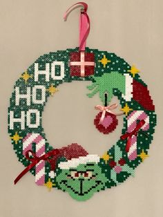 a cross stitch christmas ornament hanging on a wall