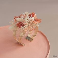 a close up of a pink cake with flowers on the top and gold trimmings