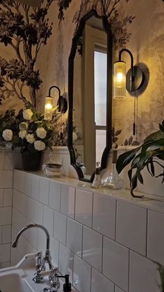 a bathroom sink sitting under a large mirror next to a wall mounted faucet