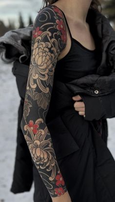 a woman with a tattoo on her arm in the snow wearing a black dress and jacket