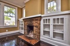 an empty living room with a fireplace and bookcases on the wall next to it