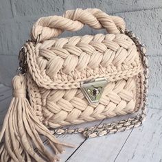 a white purse sitting on top of a wooden floor next to a wall with a chain