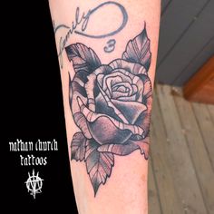 a black and white rose tattoo on the arm with an o in the middle,