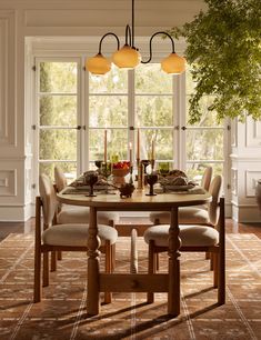 a dining room table with four chairs and a potted tree in the corner on one side