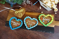 three heart shaped cookies are on a wooden board next to some popcorn boxes and flowers