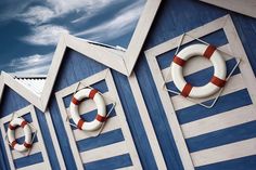 several life preservers on the side of a blue and white building under a cloudy sky