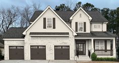 a two story white house with brown garage doors and black shutters on the front