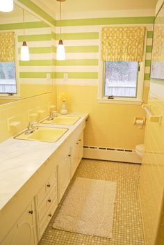 a bathroom with yellow and green stripes on the walls, two sinks in the middle