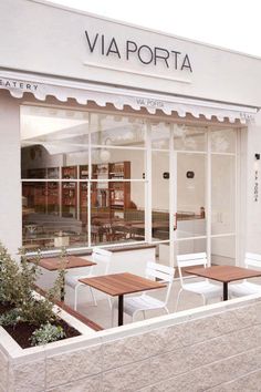 the outside of a restaurant with tables and chairs in front of it's windows