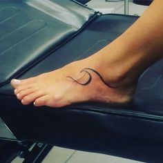 a woman's foot with a wave tattoo on it