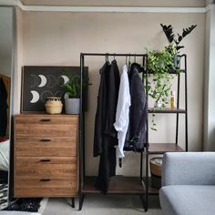 an open closet with clothes and plants in it, next to a couch on the floor