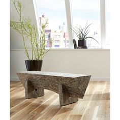 a wooden bench sitting on top of a hard wood floor next to a planter