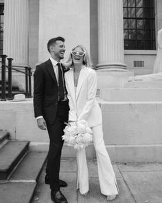 a man and woman standing next to each other in front of a building with columns