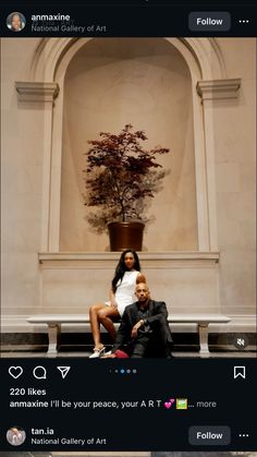 a man and woman sitting on a bench in front of a building with a tree