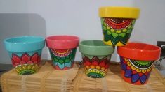 four colorful cups sitting on top of a bamboo table