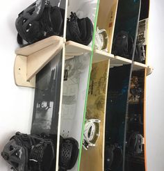 several snowboards are lined up on the wall and hanging from shelves in front of them