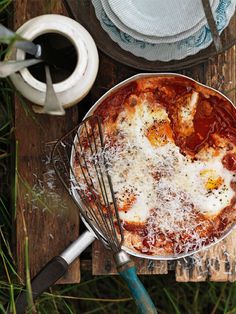 a pizza sitting on top of a metal pan next to a whisk and spatula