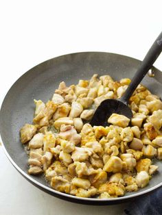 a pan filled with food on top of a white counter next to a black spatula