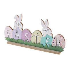 a wooden sign that says easter with three bunnies in the shape of eggs and grass