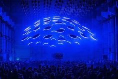 a large group of people standing in front of a stage with blue lights on it