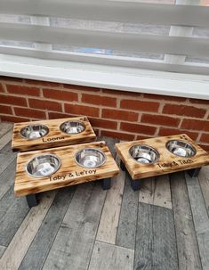 three wooden dog bowls with engraved names on them sitting in front of a brick wall