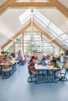 children are sitting at desks in the middle of a room with high vaulted ceilings